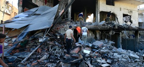 Five people searching through the remains of a bombed out building in Lebanon.